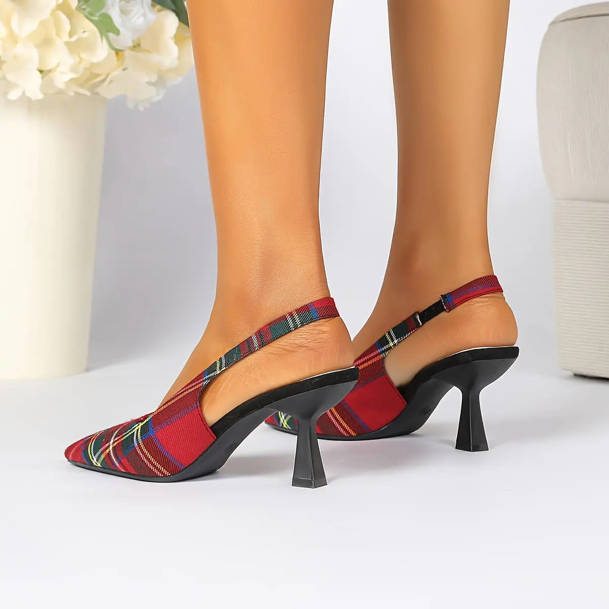 Detailed view of the stiletto heel on fashionable plaid mules.