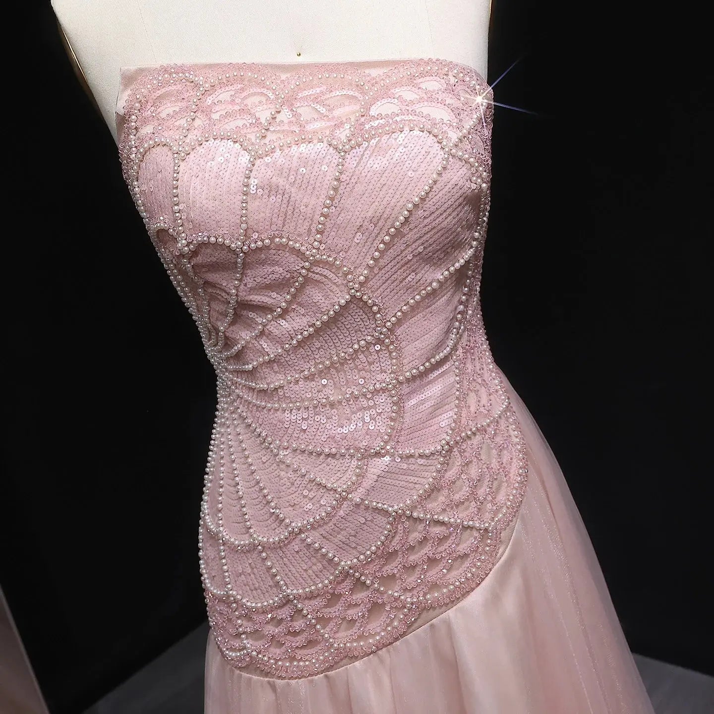 Strapless design of the blush gown highlighting shoulders and neck elegantly.