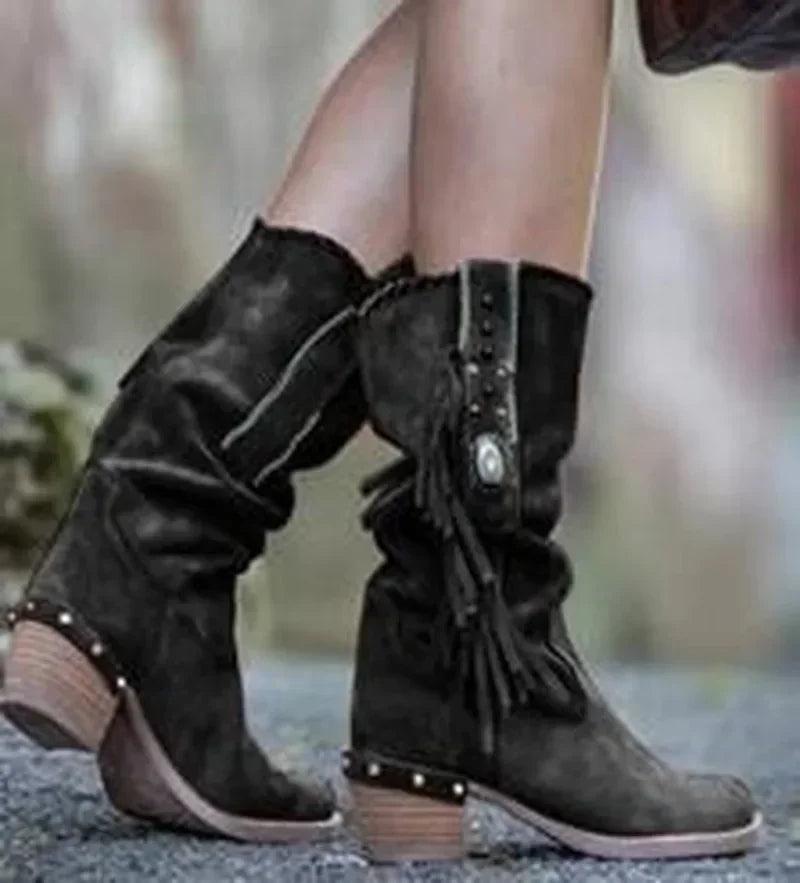 Side view of slip-on mid-calf boots featuring playful tassel accents and metal embellishments