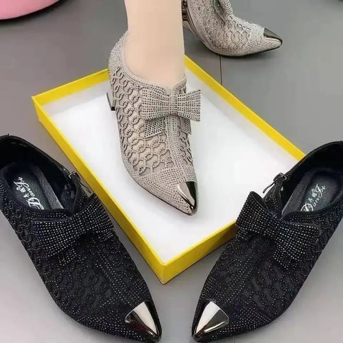 Close-up of black pumps showcasing rhinestone details and pointed toe design.