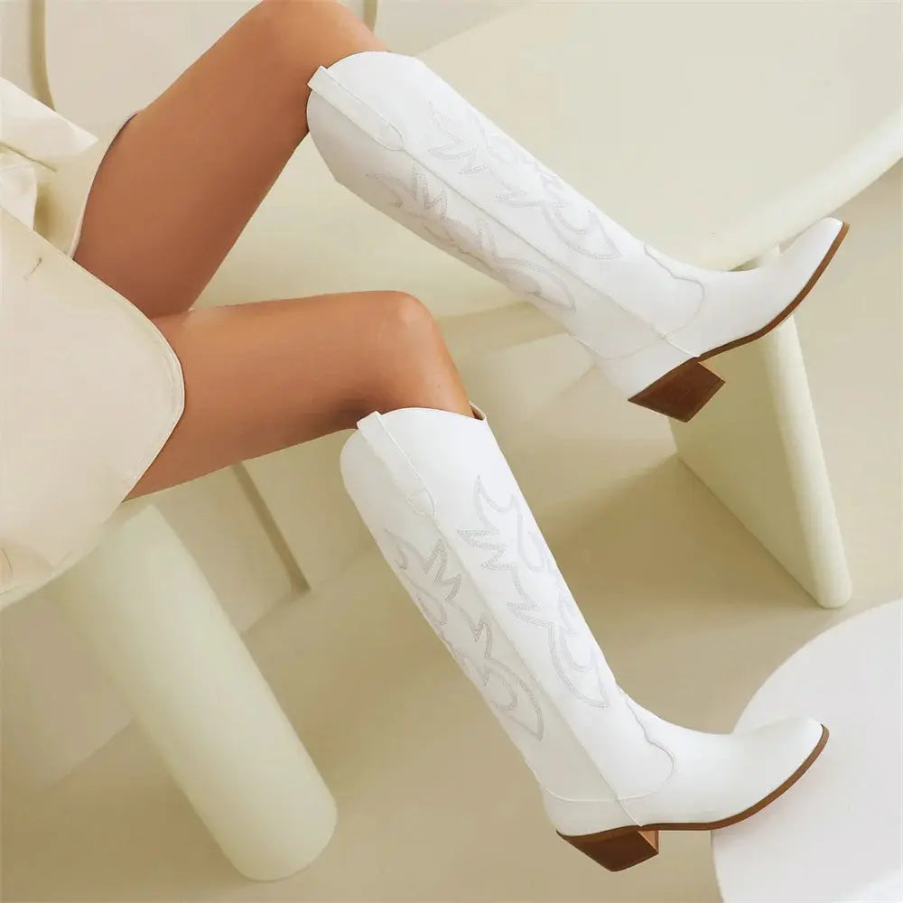 Side view of vegan leather Western boots with ornate embroidery, mid-block heel, and knee-high shaft for versatile styling