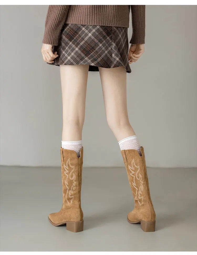 Full-length view of tan leather knee-high boots with decorative embroidery