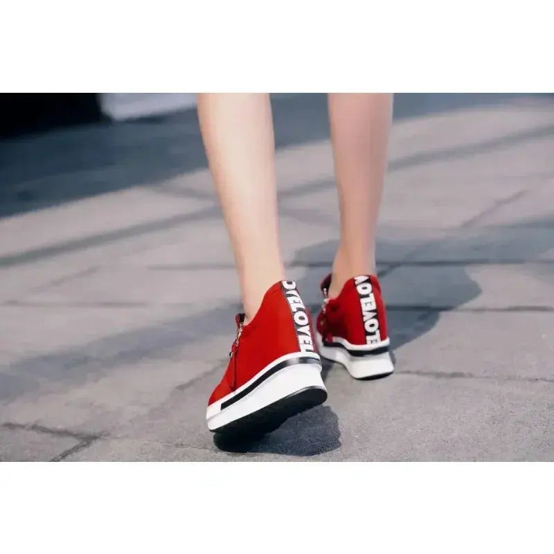 Side view of red wedge sneakers featuring zip closure for easy wear.