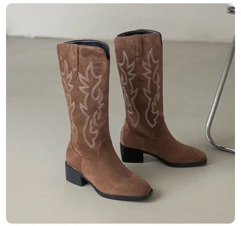 Western boots with totem embroidery catching light on polished surface