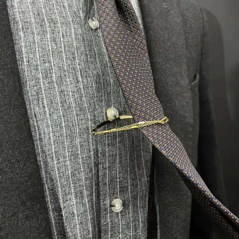 Gold tie chain attached to navy necktie showing secure positioning on dress shirt