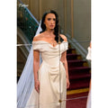 Elegant off-shoulder wedding gown in white with intricate lace embroidery and a court train.