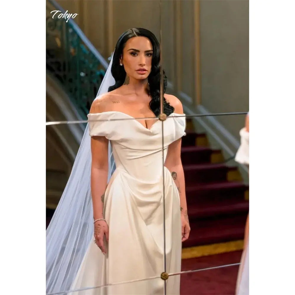 Elegant off-shoulder wedding gown in white with intricate lace embroidery and a court train.