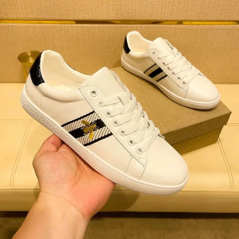 Side view of embroidered leather sneakers showing signature bee artwork and durable microfiber panel construction