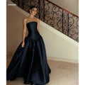 Custom satin evening gown in deep navy, featuring a sleek strapless design and floor-length skirt.