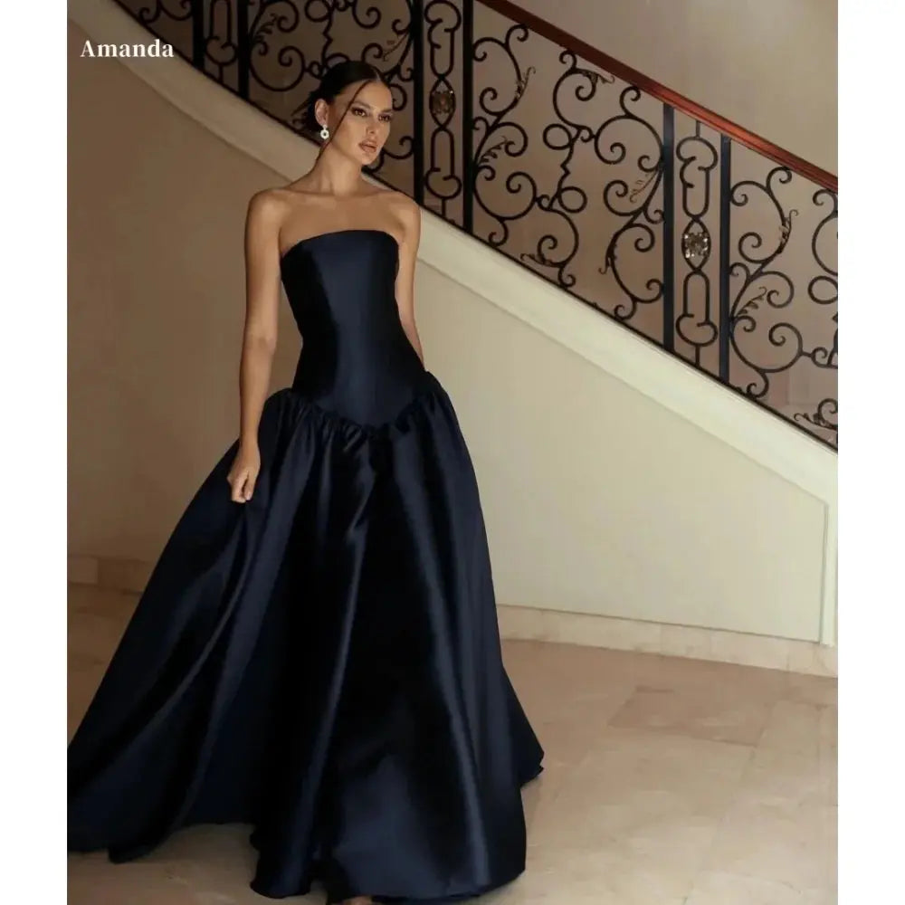 Custom satin evening gown in deep navy, featuring a sleek strapless design and floor-length skirt.