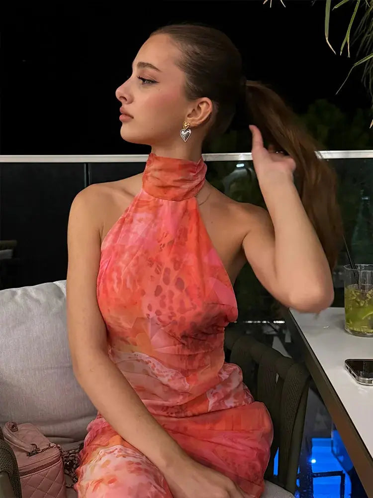 Woman wearing curve-hugging halter neck dress with mesmerizing print and open back detail