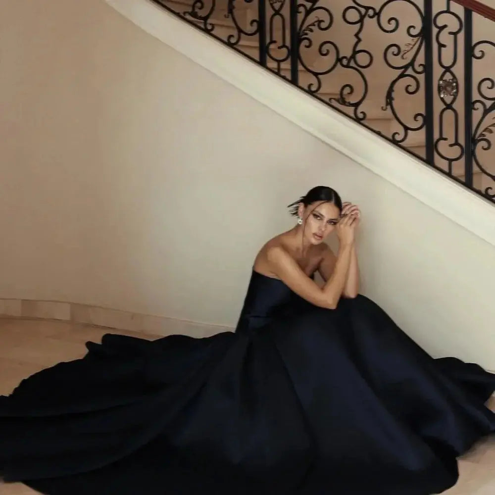 Model wearing the strapless formal gown, exuding elegance at a gala event with a stunning backdrop.
