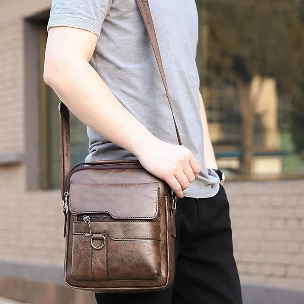 Men's vintage PU leather crossbody bag with multiple pockets hanging on white background