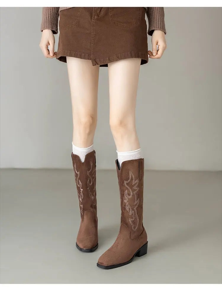 Woman's legs in embroidered knee-high cowboy boots walking on city street