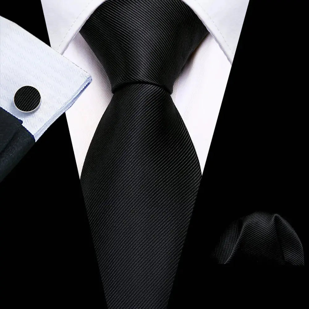 Stylish black silk tie with coordinated cufflinks and pocket square