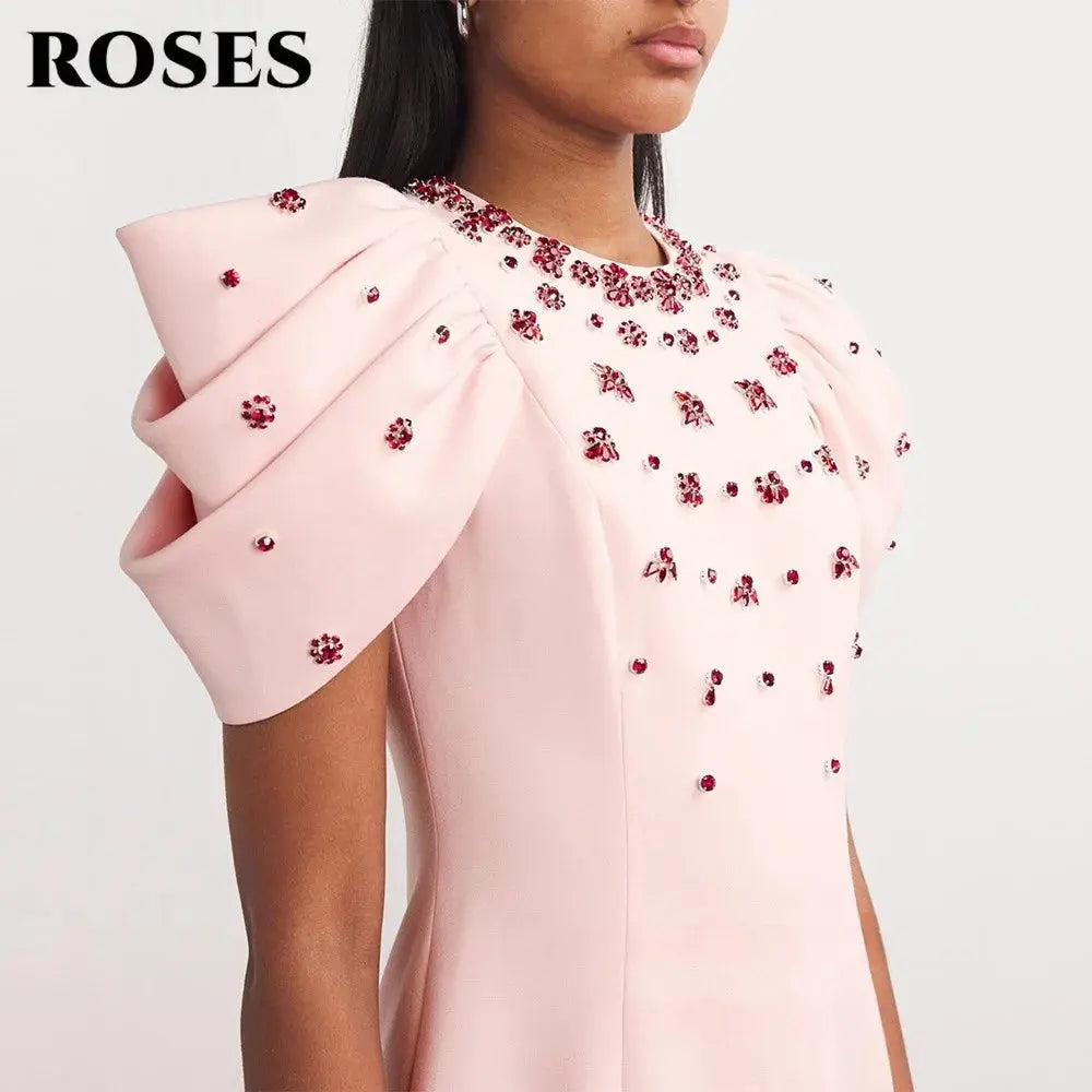 Ankle-length pink satin dress with intricate pleats and appliqués.