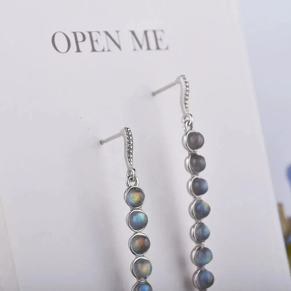 Close-up of handcrafted sterling silver earrings with shimmering labradorite reflecting light.