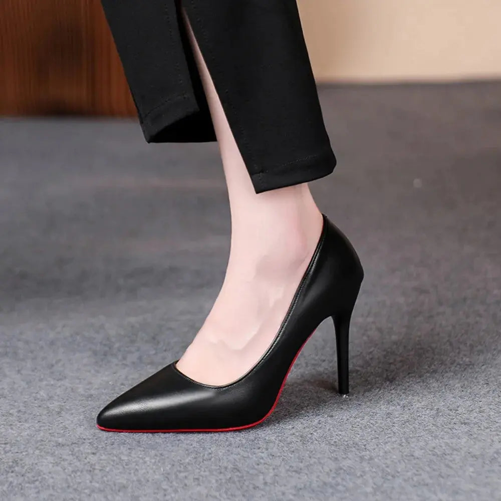 Black pointed heels on a polished surface, reflecting their sophisticated style.