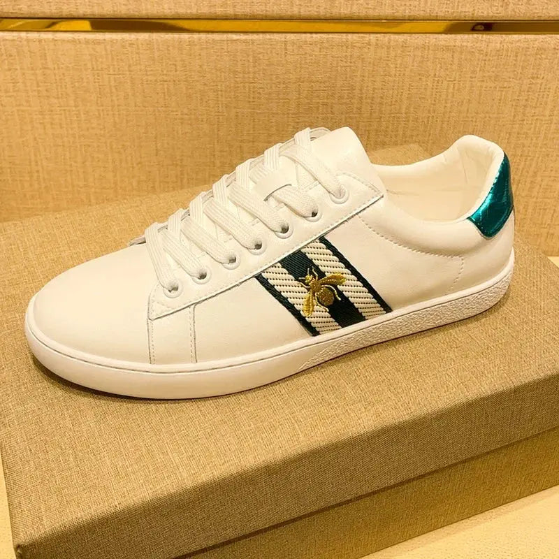 Pair of white genuine leather skate shoes with signature bee embroidery and sleek microfiber finish